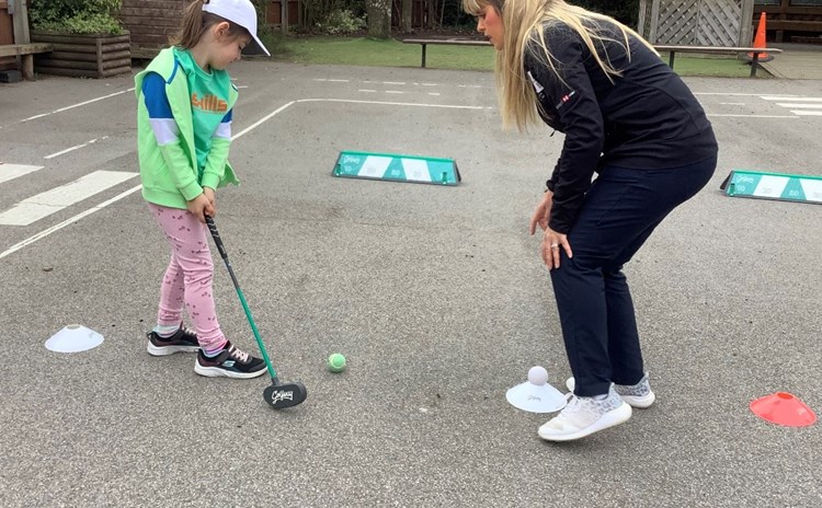 Child and golf instructor in school playground